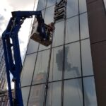 MEWP lifting a technician to install signage on the glass facade of a Unite Students building